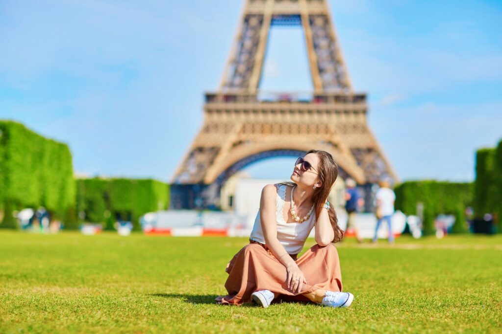 A person sitting on grass in front of the eiffel tower